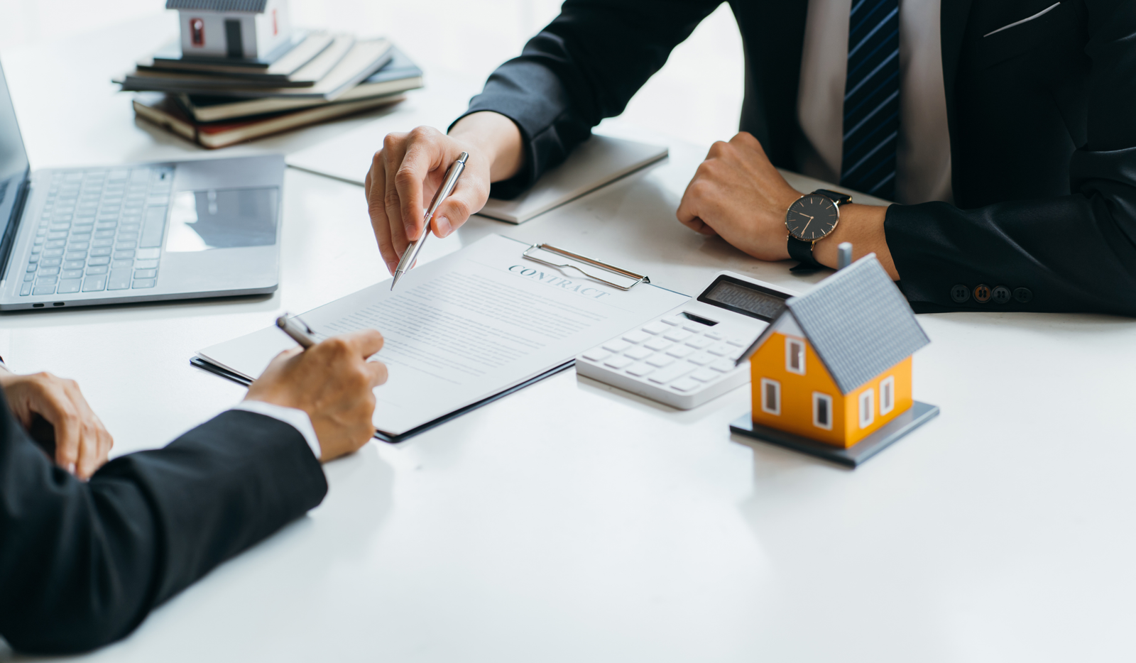 An attorney and client reviewing estate planning documents beside a small model house